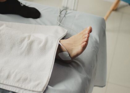 A person receives electrical stimulation therapy on their ankle, illustrating EMS vs TENS device use for pain relief.