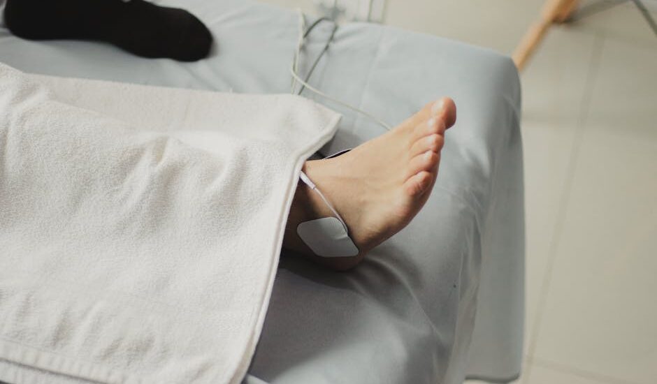 A person receives electrical stimulation therapy on their ankle, illustrating EMS vs TENS device use for pain relief.