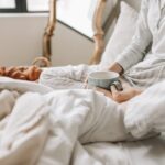A relaxing morning scene with a woman enjoying coffee in bed with warm blankets and croissants.