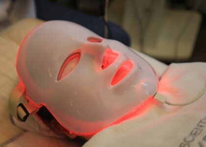 Person using a red light therapy mask, illustrating how these devices work for skin treatment in the article topic.