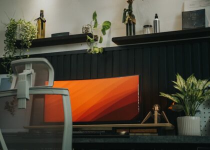 Stylish home office setup featuring a curved monitor, ergonomic chair, and indoor plants for a modern workspace vibe.