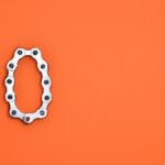 Bicycle chain arranged to form the number ten against a bright orange background.