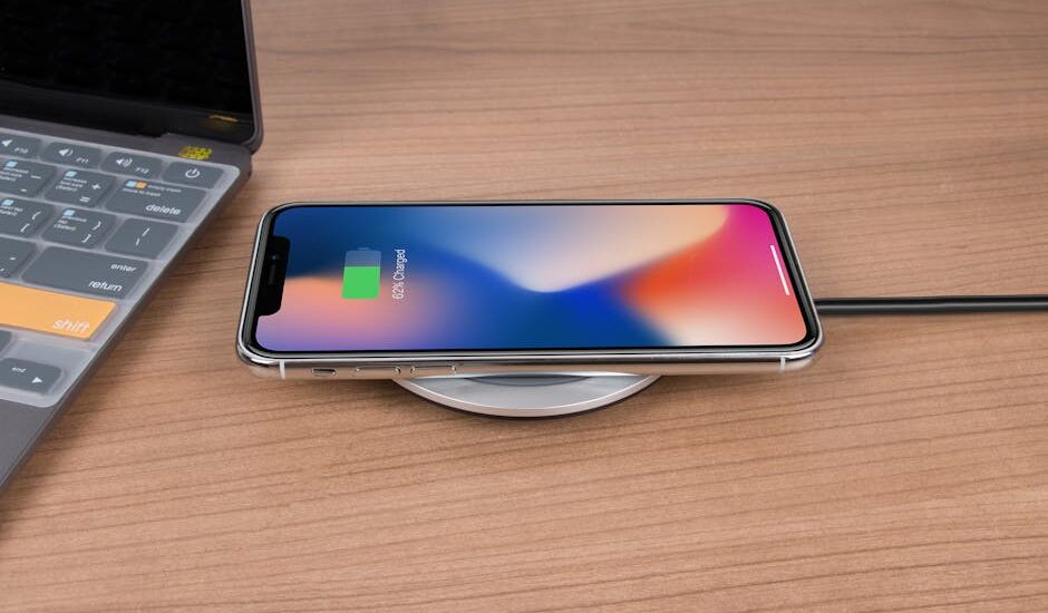 A smartphone charging wirelessly on a round charging pad next to a laptop, illustrating charging technology for the electric heating pad guide.