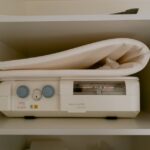 A breast pump machine with control dials and a folded pad on a shelf, illustrating breast pump options for new parents.
