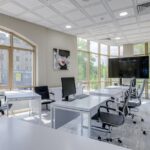 Contemporary minimalist office with glass windows and ergonomic chairs.