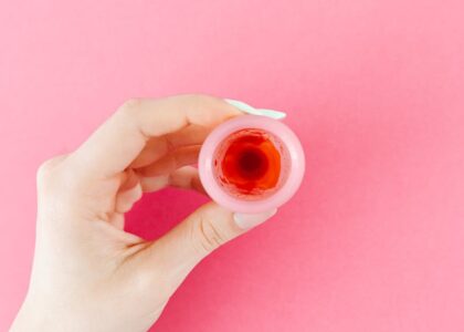 Close-up of a hand holding a menstrual cup with liquid, illustrating menstrual cup selection for first-time buyers