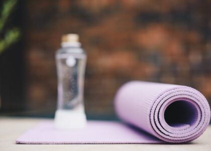 A rolled purple fitness mat and a clear spray bottle, illustrating cleaning tips for maintaining a germ-free workout space