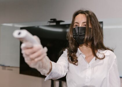 Woman wearing face mask using an infrared thermometer indoors.