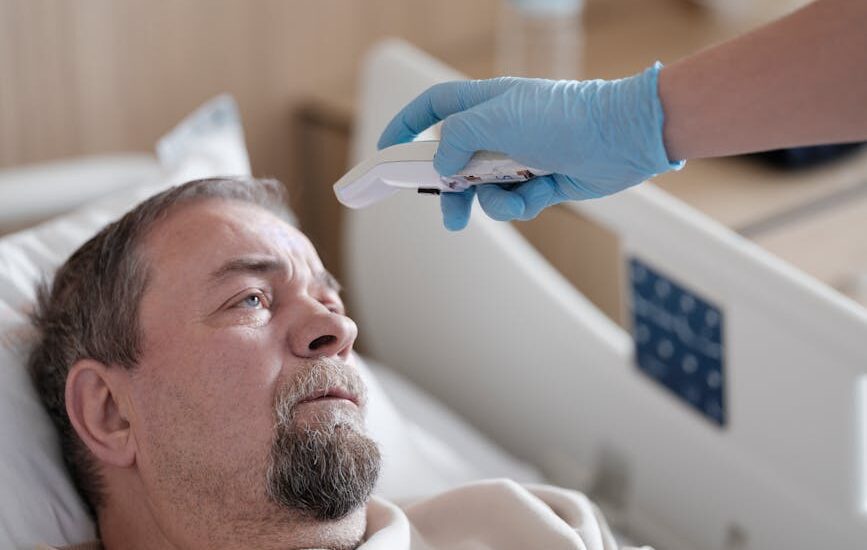Healthcare worker uses an infrared thermometer on a patient’s forehead, illustrating accuracy differences between thermometer types.