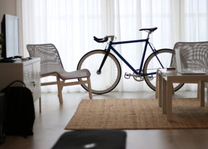 A standard bicycle stands between two chairs and a coffee table in a bright home office, illustrating workspace fitness ideas for desk cycle discussions.