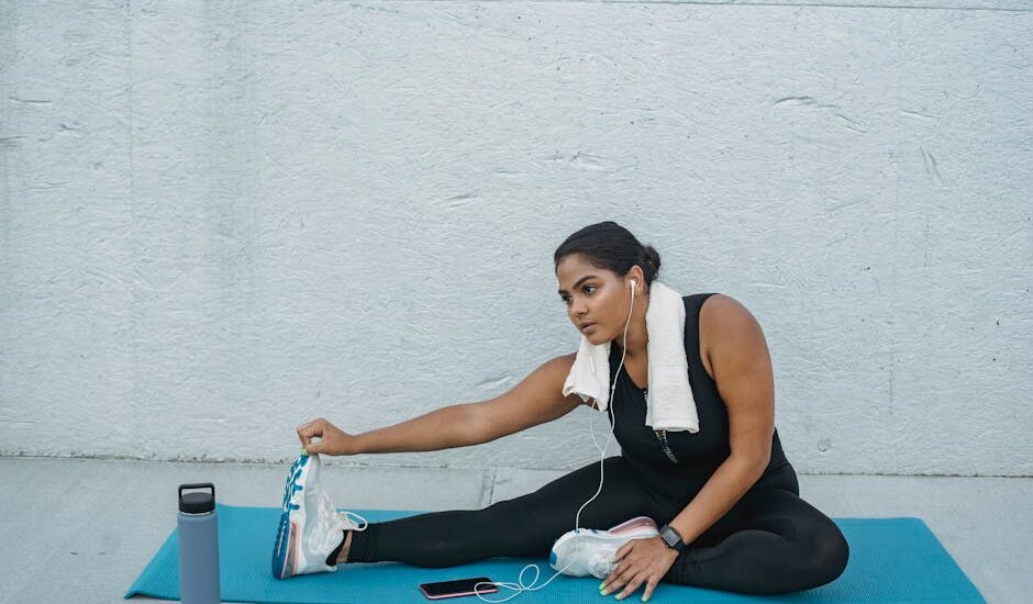 A woman stretches on a yoga mat with a towel, phone, and a smart water bottle nearby, illustrating hydration tech use.