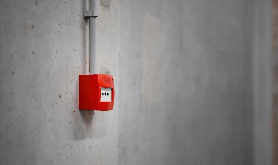 A red alarm box mounted on a gray concrete wall, offering urban security.