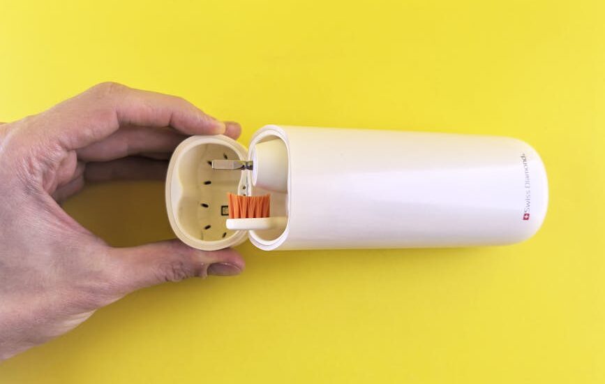 A hand opens a portable UV toothbrush sanitizer case with a toothbrush inside, illustrating travel-friendly oral hygiene solutions.