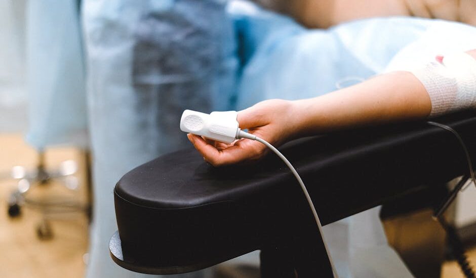 A detailed view of a patient's hand with a pulse oximeter in a medical clinic setting.