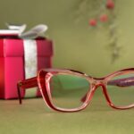 Close-up of red glasses with festive gifts and decorations in the background.