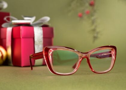 Close-up of red glasses with festive gifts and decorations in the background.