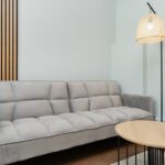 Contemporary living room featuring a grey sofa, wooden accents, and a woven lamp for a minimalist look.