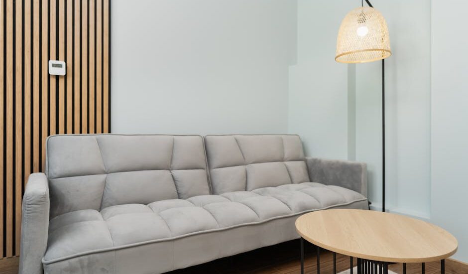 Contemporary living room featuring a grey sofa, wooden accents, and a woven lamp for a minimalist look.