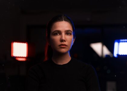 A woman sits indoors between illuminated red and blue light therapy panels, illustrating home use of red light therapy devices.
