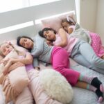 Four girls asleep in bed during a cozy sleepover, showcasing childhood bonding and friendship.