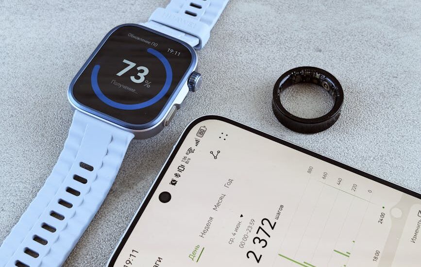 A smart ring, fitness band smartwatch, and smartphone with health data illustrate the smart ring vs fitness band topic.