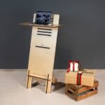 A modern wooden standing desk with a laptop and gift boxes on a crate, perfect for a minimalist office setup.