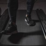 Close-up of a person’s legs in athletic shoes walking on a treadmill, illustrating staying active at work with under desk treadmills.