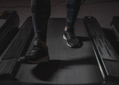 Close-up of a person’s legs in athletic shoes walking on a treadmill, illustrating staying active at work with under desk treadmills.