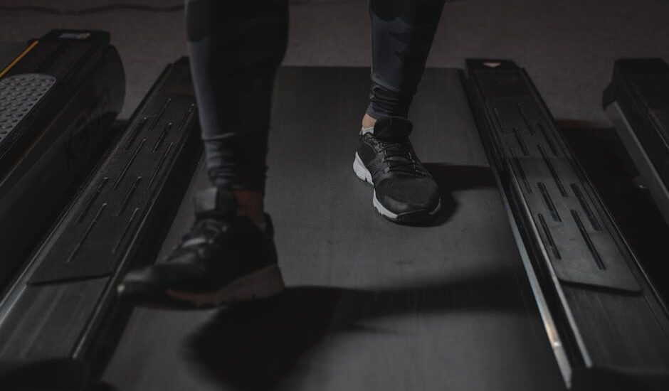 Close-up of a person’s legs in athletic shoes walking on a treadmill, illustrating staying active at work with under desk treadmills.