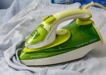 top electric heating pads — Green Philips EcoCare iron on a wrinkled shirt, ready for ironing.
