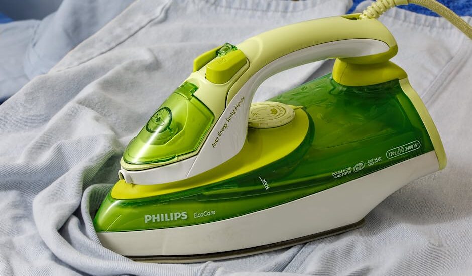 top electric heating pads — Green Philips EcoCare iron on a wrinkled shirt, ready for ironing.
