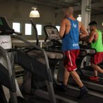 Two men running on treadmills in a modern gym, promoting fitness and health.