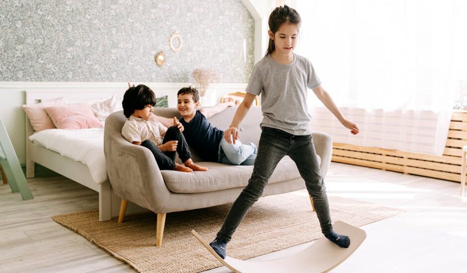 Three kids enjoying a balance board activity in a cozy bedroom setting.