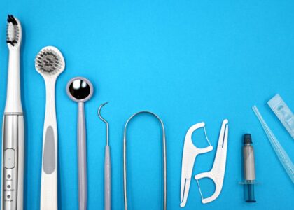 water flosser vs dental pick — Flat lay of dental care tools including toothbrushes, dental mirror, and floss sticks on blue background.
