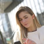 Woman using a discreet in-ear hearing aid while checking her smartphone, illustrating best hearing aids in 2026