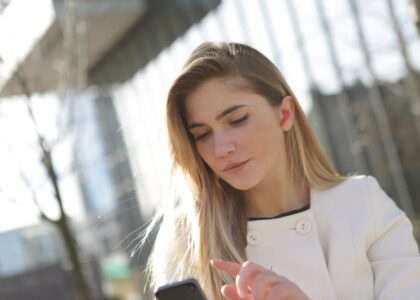 Woman using a discreet in-ear hearing aid while checking her smartphone, illustrating best hearing aids in 2026