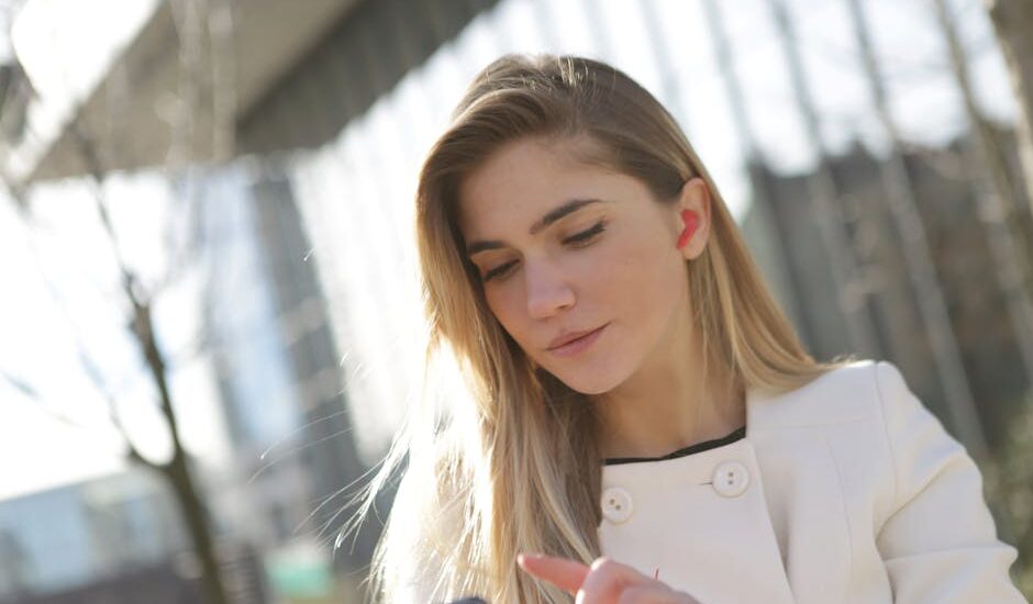 Woman using a discreet in-ear hearing aid while checking her smartphone, illustrating best hearing aids in 2026