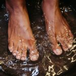 Close-up of male feet soaking in water for a relaxing spa treatment.