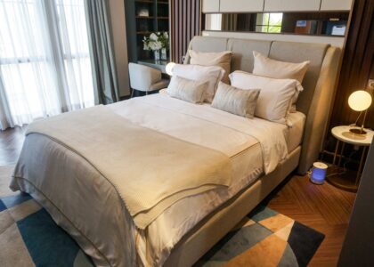 A neatly made bed in a contemporary bedroom with an air purifier positioned beside the nightstand, illustrating bedroom placement tips.