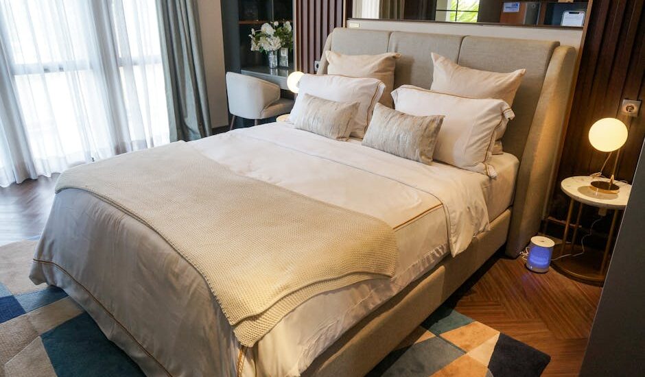 A neatly made bed in a contemporary bedroom with an air purifier positioned beside the nightstand, illustrating bedroom placement tips.