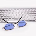 Blue light glasses resting on a keyboard, relating to blue light benefits.