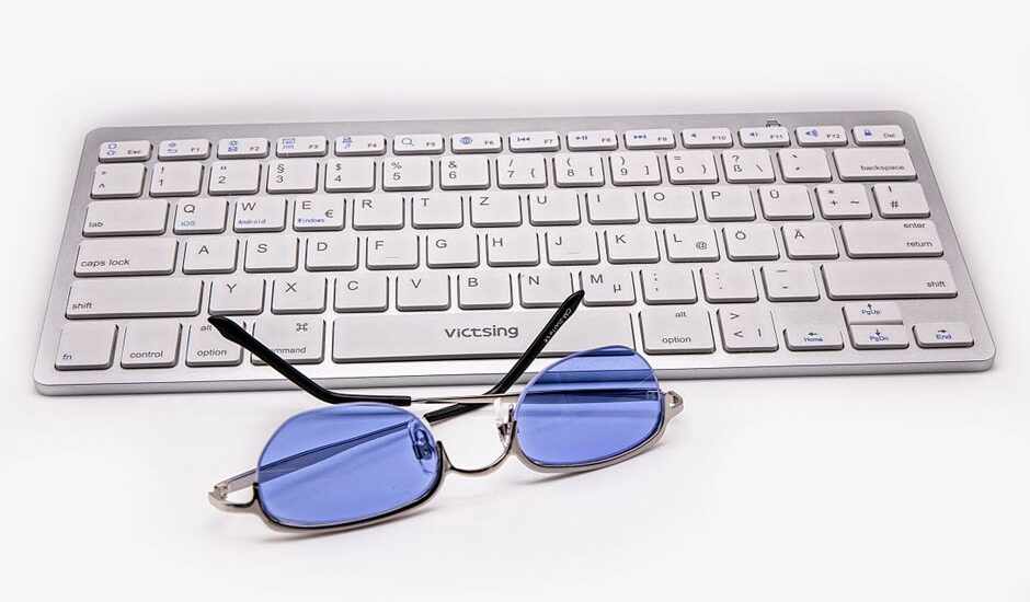 Blue light glasses resting on a keyboard, relating to blue light benefits.