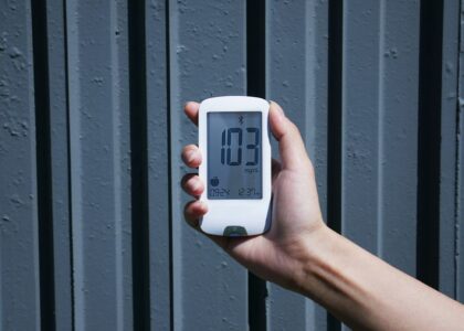 A hand holding a Bluetooth blood glucose meter displaying a reading, relevant to the best Bluetooth blood glucose meters.