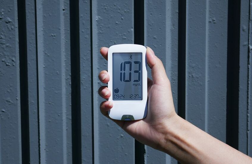 A hand holding a Bluetooth blood glucose meter displaying a reading, relevant to the best Bluetooth blood glucose meters.