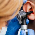 A healthcare professional examines an ear with a digital otoscope, relevant for home use.
