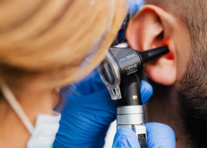 A healthcare professional examines an ear with a digital otoscope, relevant for home use.