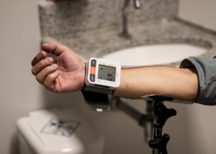 A person checks their blood pressure with a monitor on their wrist, relevant to blood pressure monitors reviews.
