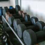 A rack displaying various dumbbells, illustrating the difference between dumbbells and kettlebells.