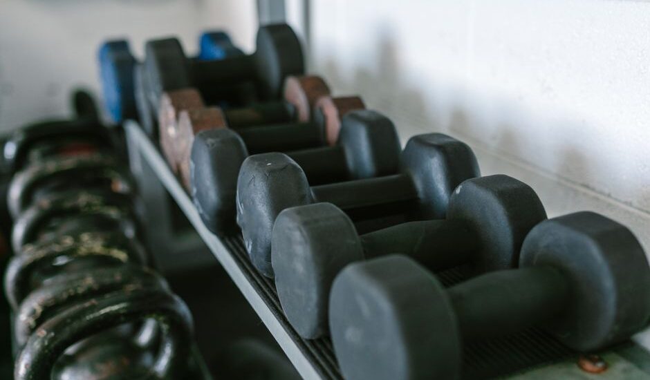 A rack displaying various dumbbells, illustrating the difference between dumbbells and kettlebells.