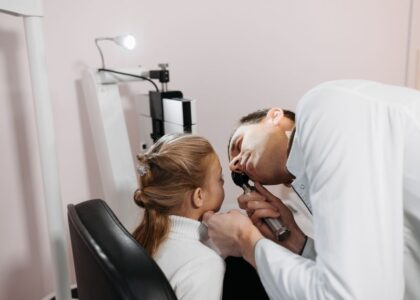 A doctor examines a child's ear, relating to hearing aids and cochlear implants.